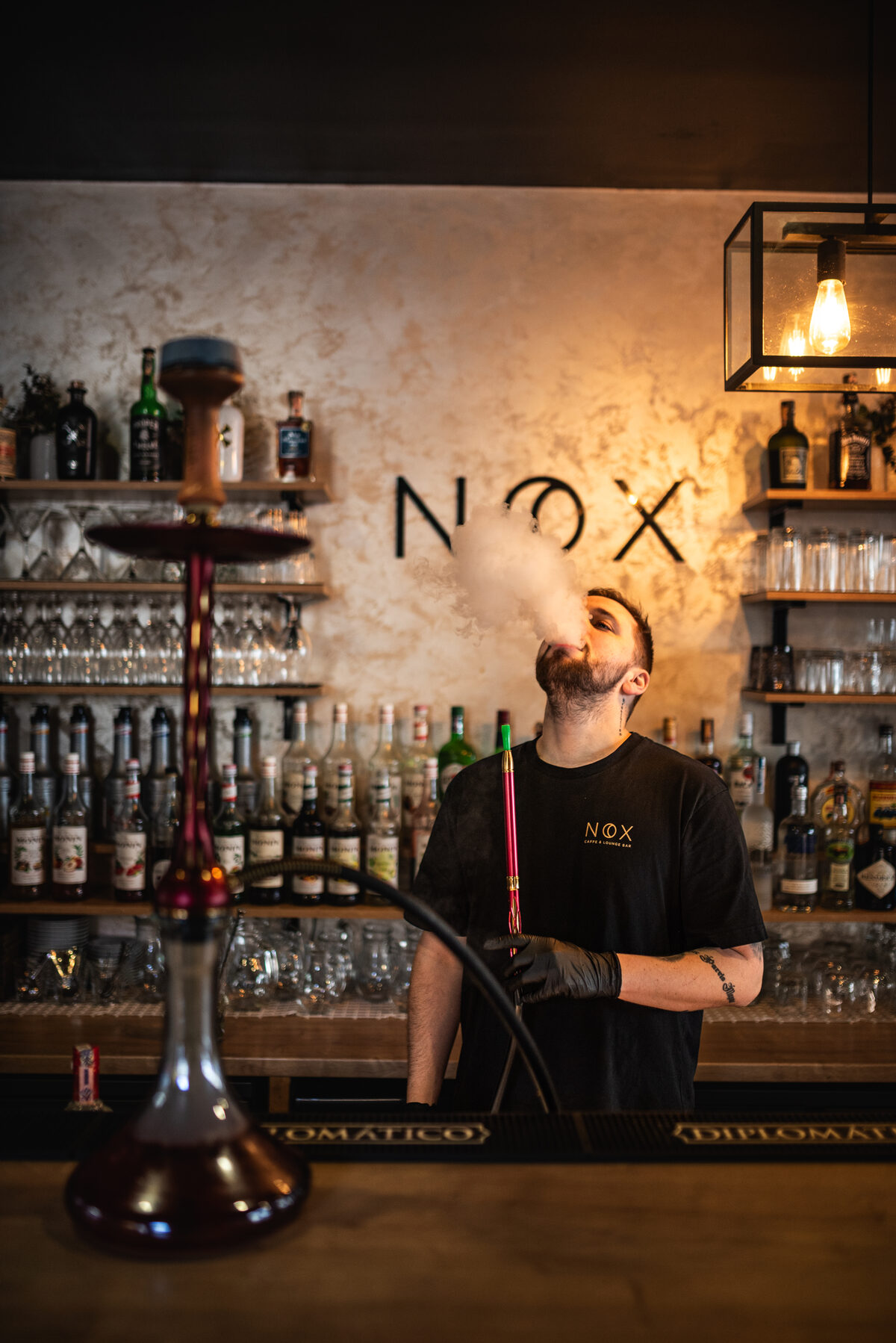 Barman pripravuje vodnú fajku za barom